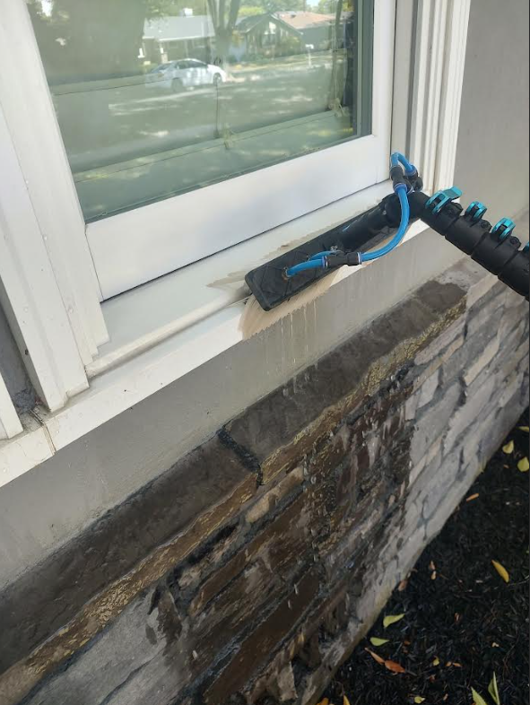 Water-fed brush cleaning a window sill and frame before the final rinse